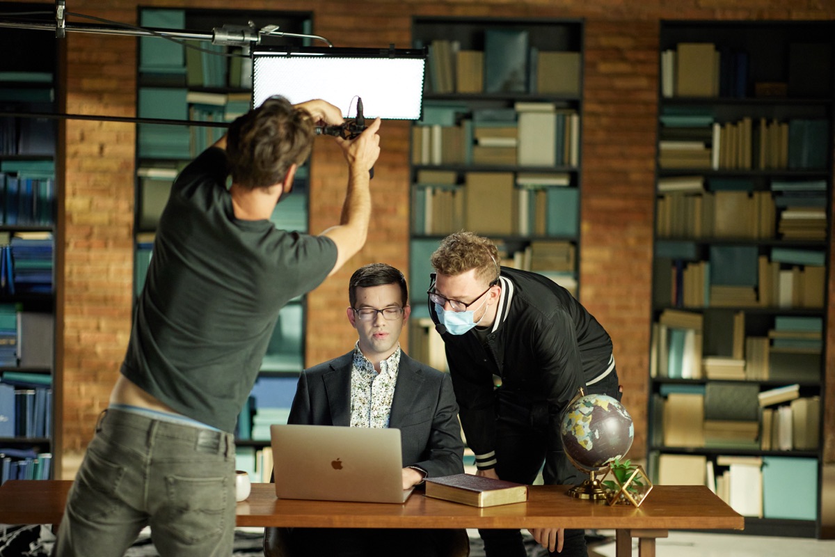 Crew adjusting lighting around Matthew Vines on set