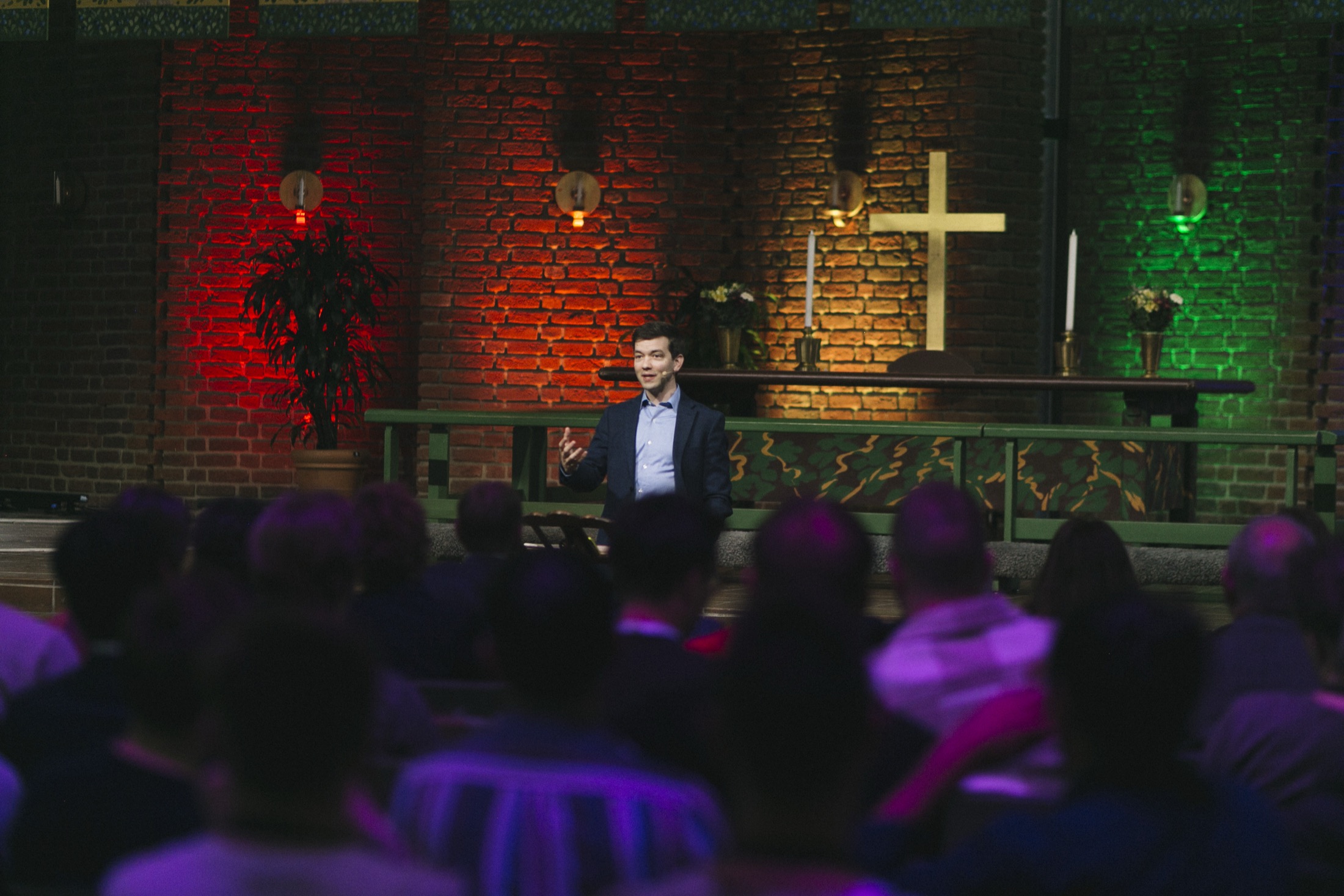 Matthew Vines speaking beneath the cross in a Swedish church, 2023